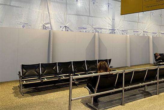 Modular walls conceal an active construction area beside airport seating.